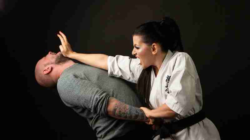 A woman in karate attire defends herself against a man in a martial arts demonstration., tags: die frauen - pexel