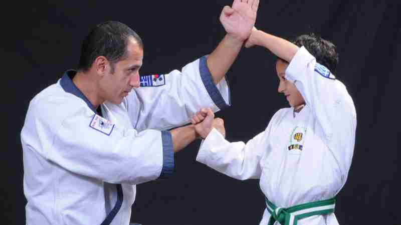An instructor and child practicing martial arts techniques in traditional uniforms., tags: tang soo - pexel