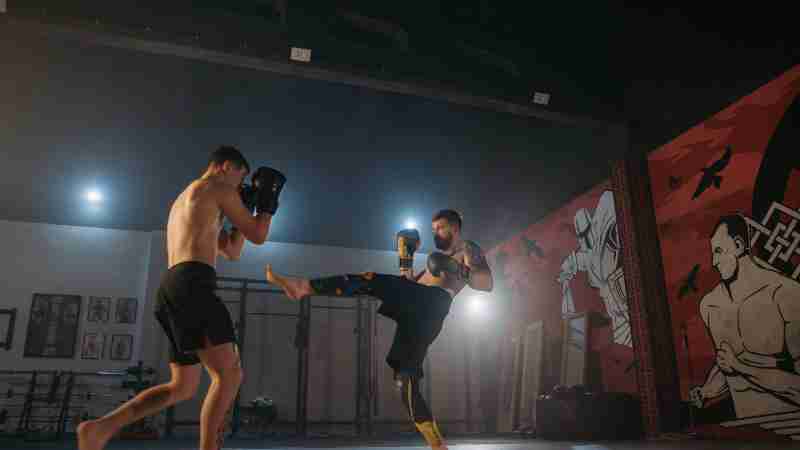Two athletes engage in a dynamic kickboxing sparring session in a well-equipped gym., tags: und schlüssel - pexel
