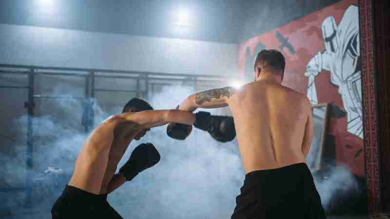 Two shirtless men sparring in a smoky gym setting, showcasing powerful boxing techniques., tags: eathan - pexel