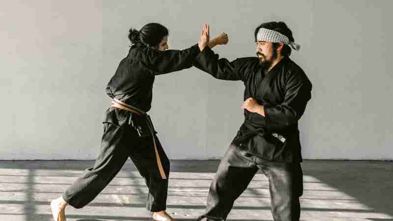 Two martial artists practice techniques in a sunlit room, showcasing discipline and skill., tags: kempo und - pexel